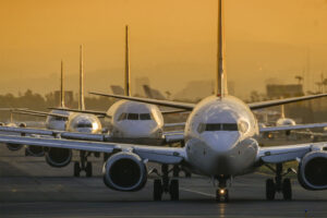Commercial aircraft lined up on a runway during sunset, symbolizing the challenge of grounding and restarting an airline fleet during the COVID-19 pandemic.